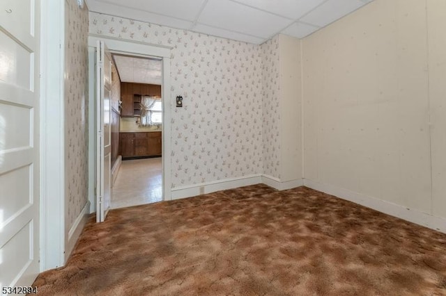 carpeted spare room with a drop ceiling, wallpapered walls, and baseboards