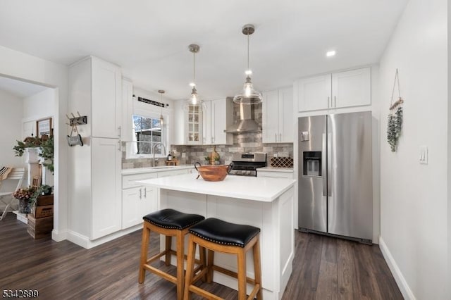 kitchen with a sink, stainless steel appliances, light countertops, wall chimney exhaust hood, and tasteful backsplash