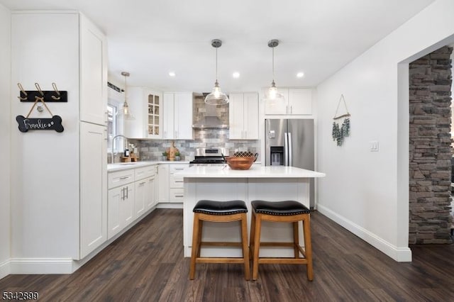 kitchen with dark wood-type flooring, a sink, tasteful backsplash, stainless steel appliances, and wall chimney exhaust hood