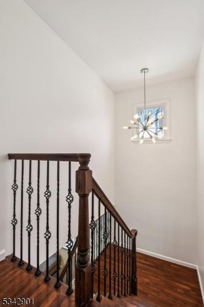 staircase featuring a chandelier, baseboards, and wood finished floors