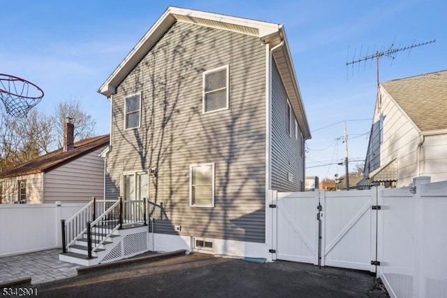 rear view of property featuring a patio area, fence, and a gate