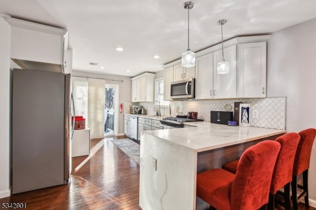 kitchen featuring dark wood-style flooring, a sink, light countertops, appliances with stainless steel finishes, and backsplash