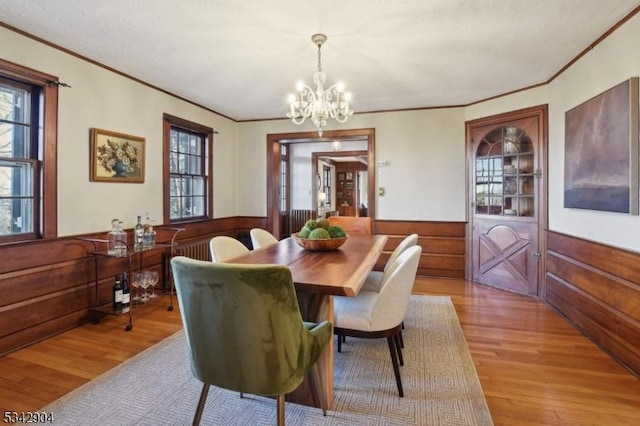 dining space with a chandelier, wood finished floors, wainscoting, and ornamental molding