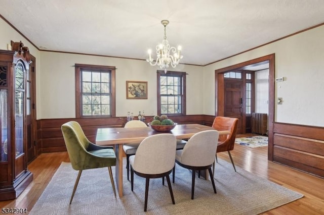 dining room featuring radiator, an inviting chandelier, light wood-style flooring, and wainscoting