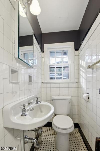 bathroom with tile patterned floors, toilet, and tile walls