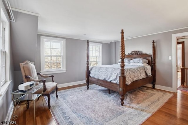 bedroom featuring ornamental molding, baseboards, and wood finished floors