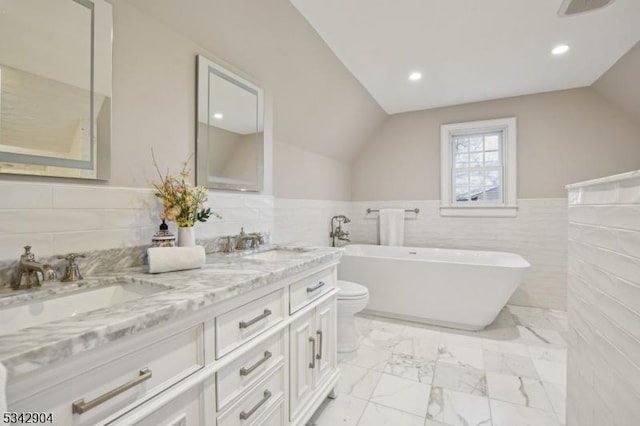 full bath featuring a freestanding tub, marble finish floor, a sink, double vanity, and lofted ceiling