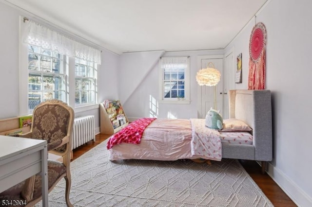 bedroom featuring baseboards, wood finished floors, and radiator heating unit