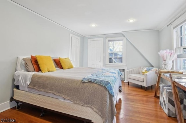 bedroom with wood finished floors, baseboards, recessed lighting, a closet, and crown molding