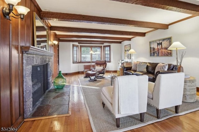 living area with hardwood / wood-style flooring, beamed ceiling, baseboards, and a high end fireplace