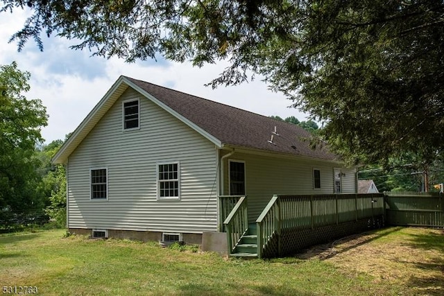 rear view of house with roof with shingles, a yard, and fence