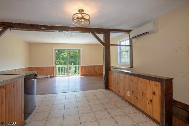 empty room with a wainscoted wall, beamed ceiling, a textured ceiling, an AC wall unit, and wood walls