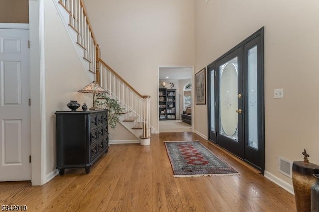 foyer entrance featuring baseboards, stairs, a towering ceiling, and wood finished floors