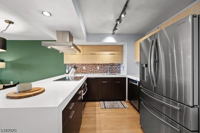 kitchen featuring light wood-type flooring, light countertops, decorative backsplash, island range hood, and black appliances