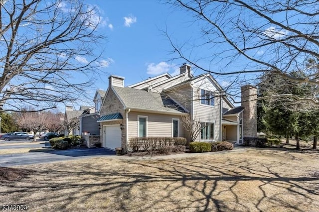 view of property exterior with aphalt driveway and a chimney