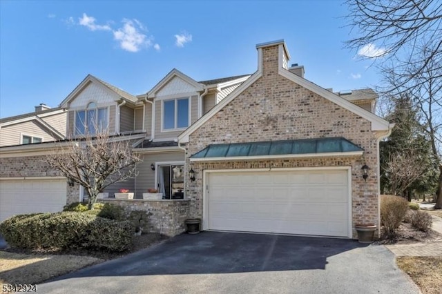 view of front of house with driveway, a chimney, and a garage