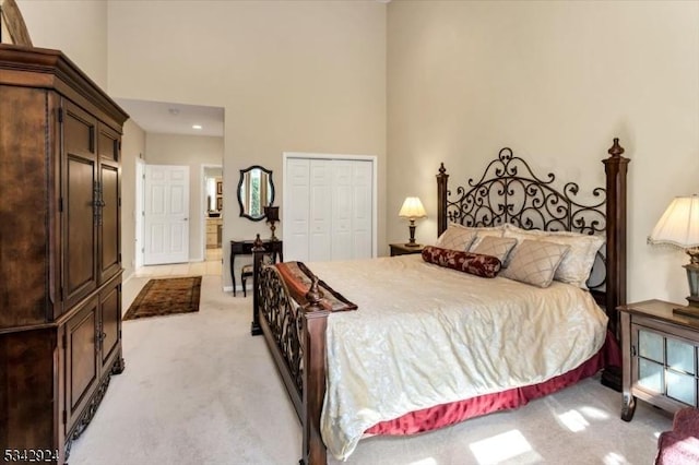 bedroom with light carpet, a high ceiling, and a closet