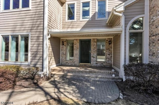 view of exterior entry featuring brick siding and a porch