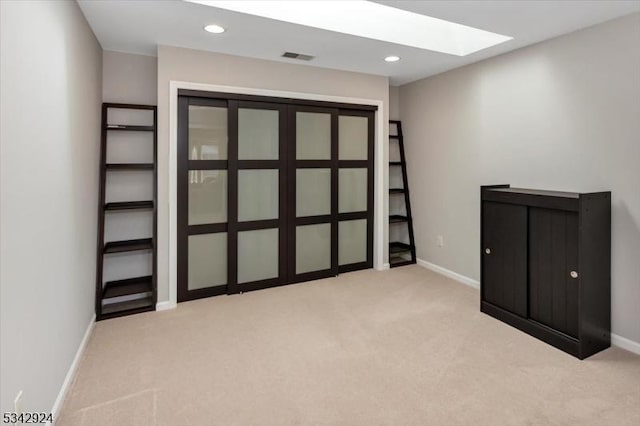 unfurnished room with recessed lighting, light colored carpet, a skylight, and baseboards