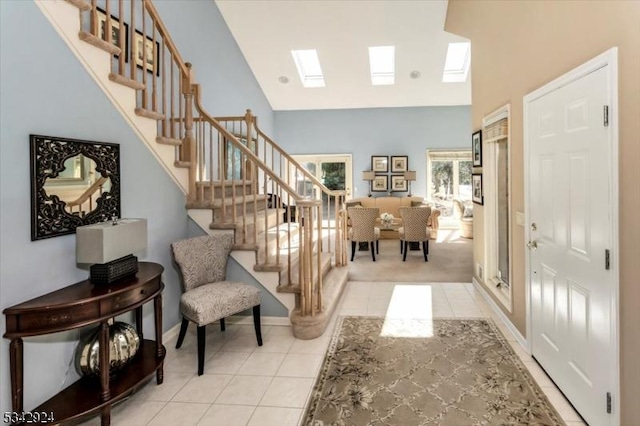 entrance foyer with light tile patterned floors, stairway, and a skylight