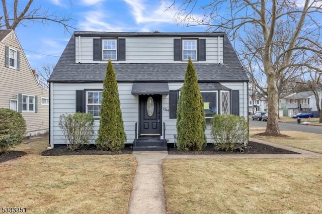 view of front of property featuring entry steps, a front lawn, and roof with shingles