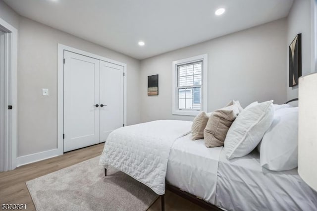 bedroom featuring light wood-style flooring, recessed lighting, a closet, and baseboards