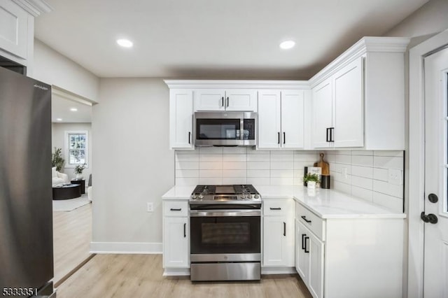 kitchen featuring tasteful backsplash, baseboards, light wood-type flooring, appliances with stainless steel finishes, and white cabinetry