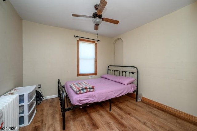 bedroom with a ceiling fan, baseboards, and wood finished floors