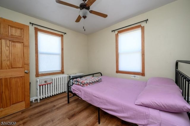 bedroom featuring radiator heating unit, wood finished floors, and ceiling fan