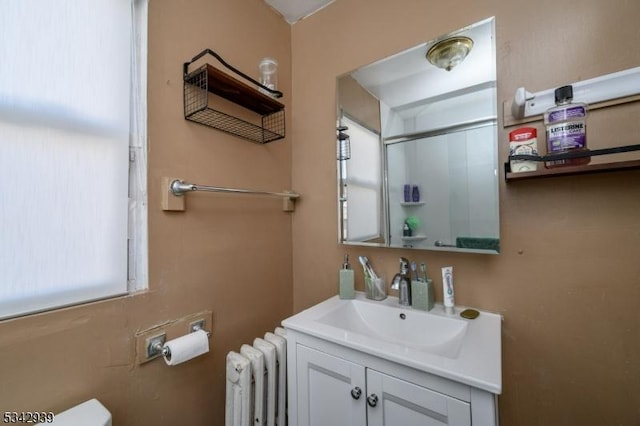 bathroom featuring toilet, radiator, and vanity