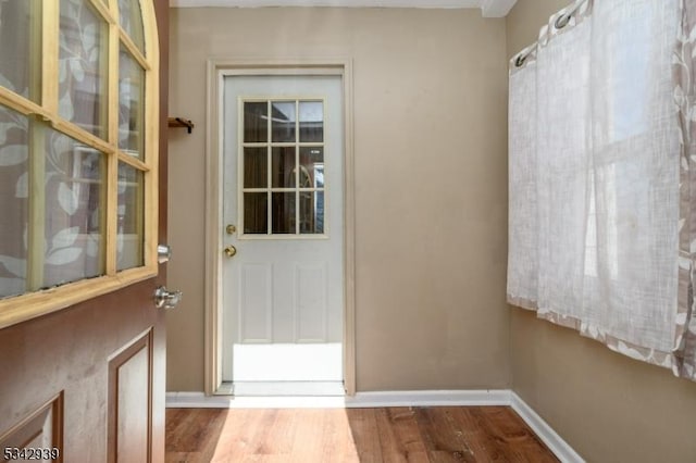 doorway to outside with baseboards and wood finished floors