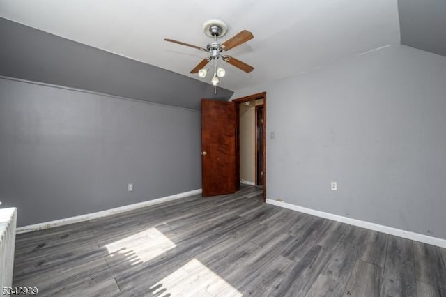 unfurnished bedroom with a ceiling fan, vaulted ceiling, wood finished floors, and baseboards