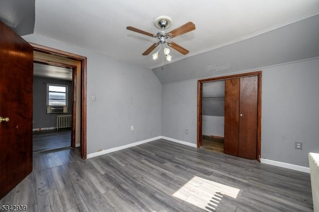 unfurnished bedroom featuring lofted ceiling, a ceiling fan, wood finished floors, radiator heating unit, and baseboards