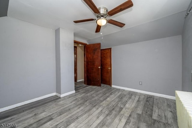 interior space featuring lofted ceiling, wood finished floors, baseboards, and ceiling fan