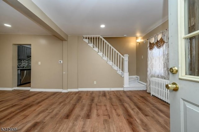 foyer with baseboards, radiator, wood finished floors, and stairs