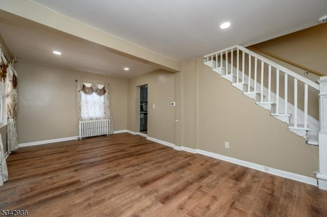 interior space featuring stairway, wood finished floors, baseboards, radiator heating unit, and recessed lighting