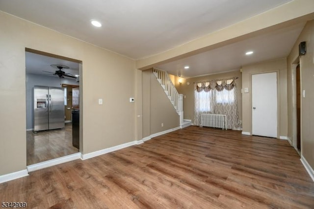 interior space with baseboards, radiator, wood finished floors, and stairs