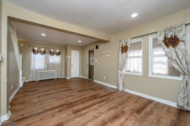 interior space featuring recessed lighting, baseboards, radiator, and wood finished floors