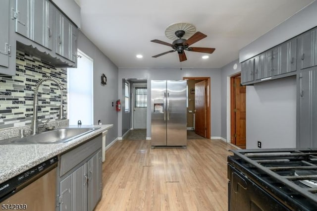 kitchen with baseboards, light wood finished floors, a sink, gray cabinetry, and stainless steel appliances