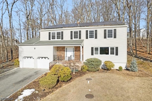 view of front of house with aphalt driveway, roof mounted solar panels, a porch, and brick siding