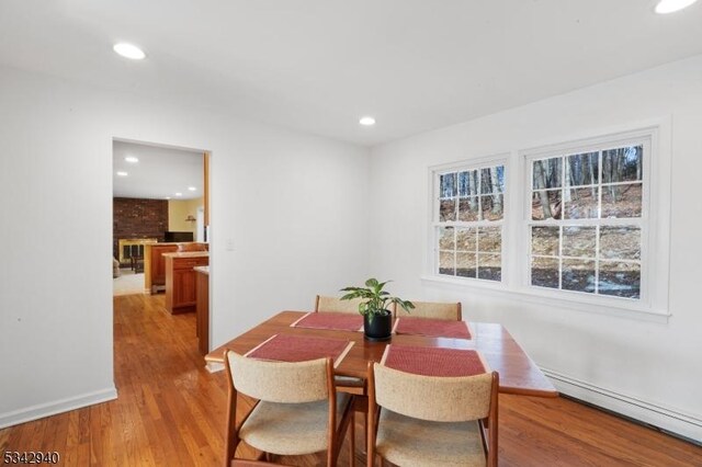 dining space with recessed lighting, a brick fireplace, light wood-type flooring, and a baseboard heating unit