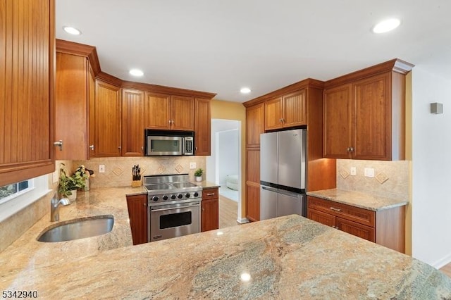 kitchen with decorative backsplash, appliances with stainless steel finishes, light stone countertops, and a sink