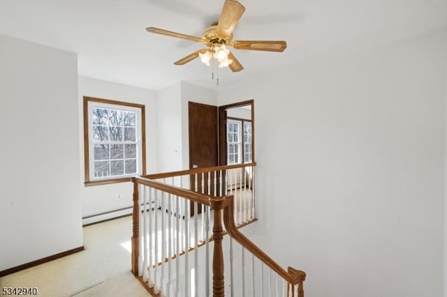 corridor with light colored carpet, an upstairs landing, baseboard heating, and baseboards