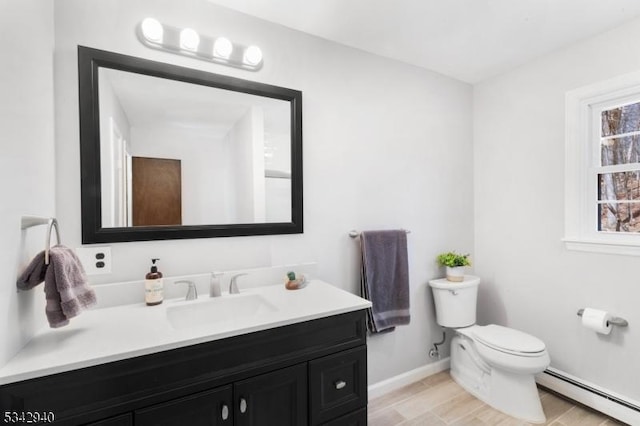 bathroom with vanity, wood finished floors, baseboards, toilet, and baseboard heating