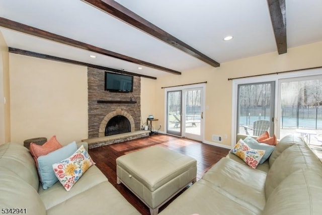 living room featuring wood finished floors, baseboards, beam ceiling, recessed lighting, and a stone fireplace