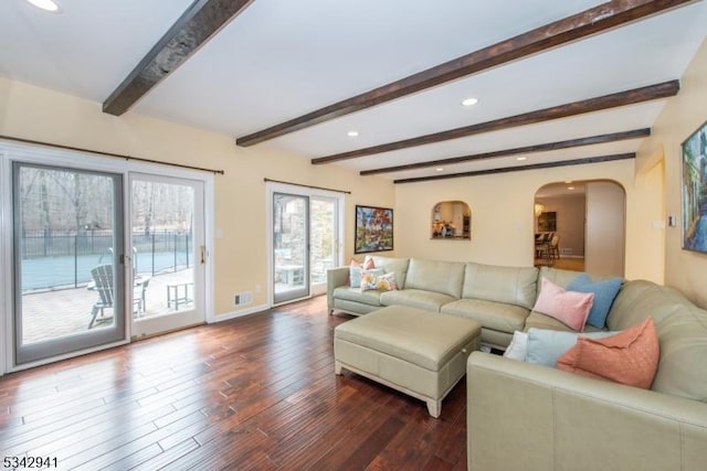 living area with dark wood finished floors, beam ceiling, recessed lighting, and arched walkways