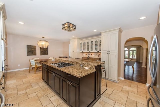 kitchen featuring stone tile floors, recessed lighting, stainless steel appliances, arched walkways, and light stone countertops