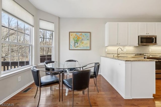 dining area with wood finished floors, visible vents, and baseboards