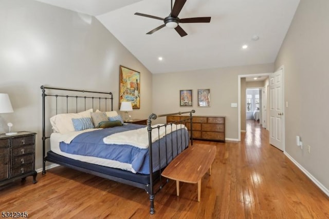 bedroom with a ceiling fan, light wood-type flooring, baseboards, and vaulted ceiling