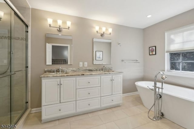 bathroom featuring double vanity, a shower stall, a freestanding bath, and a sink